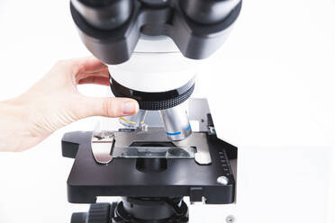 Hand of scientist adjusting microscope at laboratory - PCLF00892