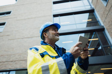 Ingenieur mit Tablet-PC in der Nähe eines Gebäudes - JOSEF22453