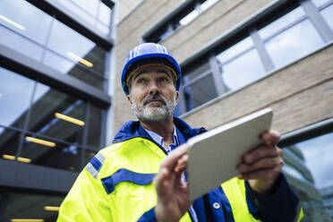 Engineer holding tablet PC in front of building - JOSEF22454