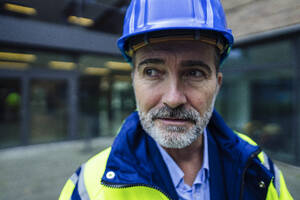 Contemplative engineer wearing blue hardhat - JOSEF22456