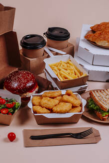 Chicken nuggets with fast foods and coffee cups against beige background  - MDOF01790