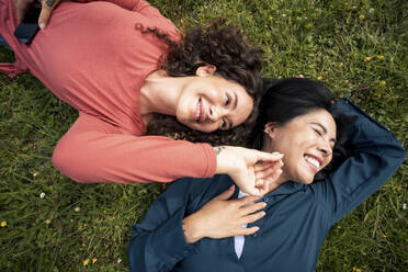 Smiling friends lying on grass in park - JOSEF22571