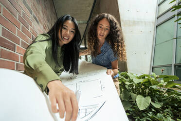 Multiracial architects examining blueprint in corridor at office  - JOSEF22590