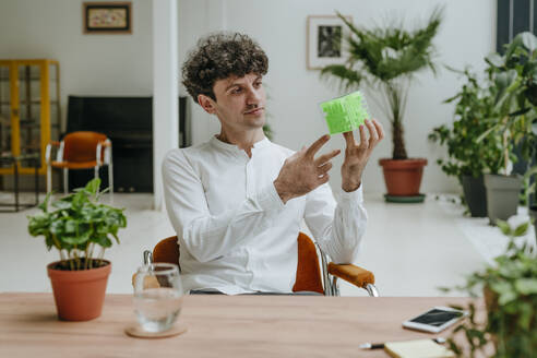 Businessman examining cube maze at desk in office - YTF01570