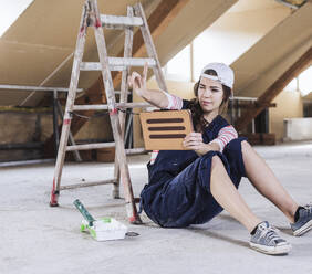 Young woman holding tablet PC and measuring with fingers at home - UUF30889