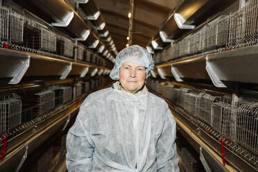 Veterinarian standing near birdcages in factory - EYAF02883