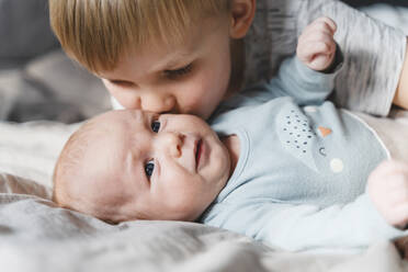 Brother kissing baby brother on cheek at home - NDEF01530