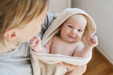 Mutter mit lächelndem, in ein Handtuch gewickeltem Babysohn zu Hause - NDEF01533