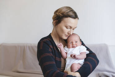 Mutter umarmt kleinen Jungen auf dem Sofa zu Hause - NDEF01548