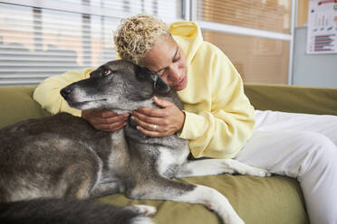 Frau umarmt Hund auf Sofa in Klinik - KPEF00532
