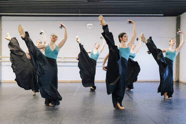 Anmutige Flamenco-Tänzerin beim Üben auf einem Bein im Studio - MRRF02748