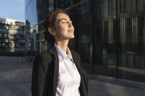 Businesswoman standing with eyes closed in city - VPIF09209