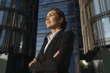 Smiling businesswoman standing with arms crossed in front of building - VPIF09213