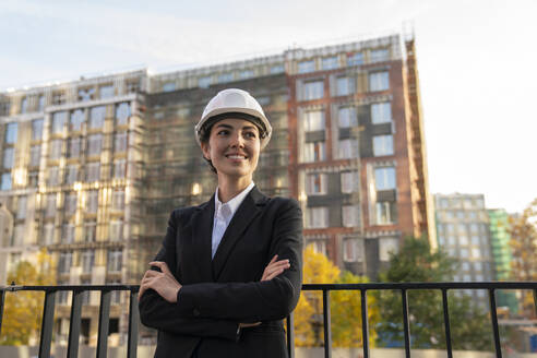 Smiling engineer standing with arms crossed near railing in city - VPIF09222