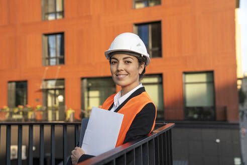 Lächelnder Ingenieur mit stehendem Aktenordner auf dem Balkon - VPIF09230