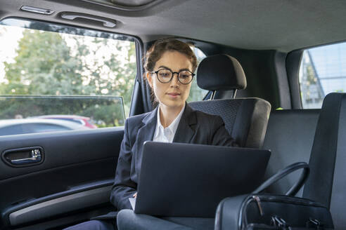 Businesswoman using laptop in car - VPIF09243