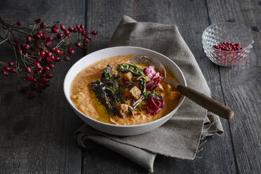 Studioaufnahme einer Schüssel mit verzehrfertiger Kürbissuppe mit Croutons und Rote-Bete-Chips - EVGF04445