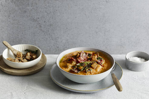 Studioaufnahme einer Schüssel mit verzehrfertiger Kürbissuppe mit Croutons und Rote-Bete-Chips - EVGF04446