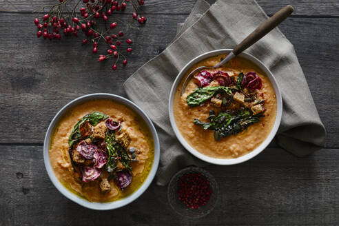 Studioaufnahme einer Schüssel mit verzehrfertiger Kürbissuppe mit Croutons und Rote-Bete-Chips - EVGF04451