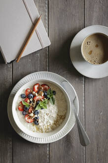 Tagebuch, eine Tasse Kaffee und eine Schüssel Porridge mit Blaubeeren und Erdbeeren - EVGF04452