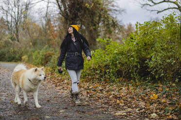 Lächelnde Frau mit Hund auf dem Fußweg im Herbstpark - JCCMF11069