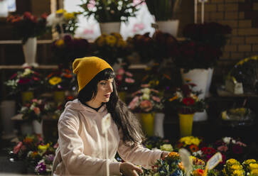 Woman wearing knitted hat and buying flowers at shop - JCCMF11075