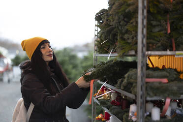 Beautiful woman buying wreath at Christmas market - JCCMF11081