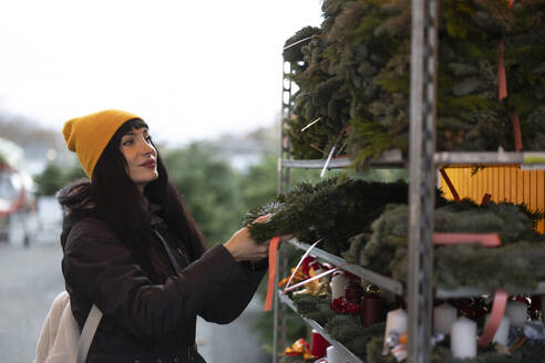 Schöne Frau kauft Kranz auf dem Weihnachtsmarkt - JCCMF11081
