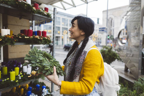 Glückliche Frau kauft Kranz auf dem Weihnachtsmarkt - JCCMF11093