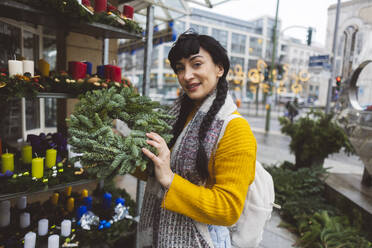 Happy woman holding wreath at Christmas market - JCCMF11095