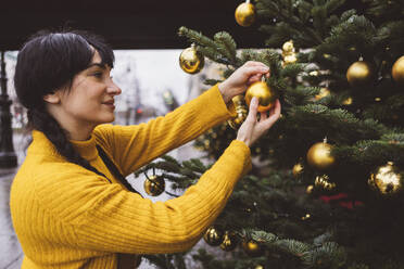 Lächelnde Frau beim Schmücken des Weihnachtsbaums - JCCMF11096