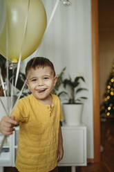 Geburtstagskind hält Luftballons zu Hause - ANAF02634