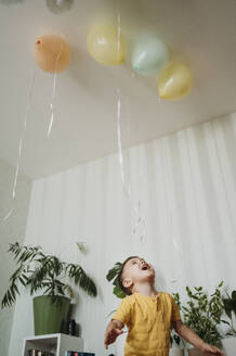 Aufgeregter Junge spielt mit Luftballons zu Hause - ANAF02635