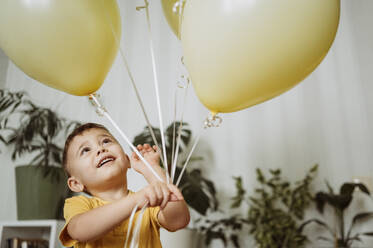 Glücklicher Junge spielt mit Luftballons zu Hause - ANAF02636