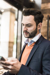 Businessman with beard using smart phone at cafe - UUF30938