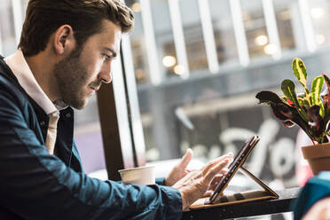 Businessman using tablet PC at cafe - UUF30939