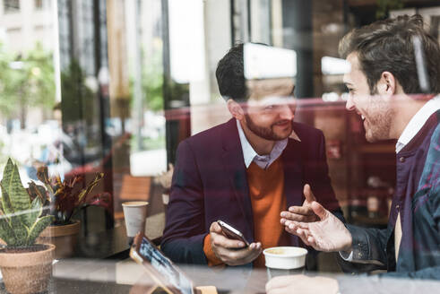 Happy businessmen discussing at cafe - UUF30942