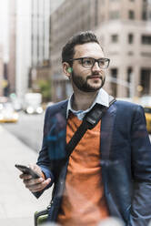 Businessman wearing eyeglasses and holding smart phone - UUF30944