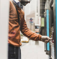 Junger Geschäftsmann an einem Geldautomaten - UUF30946