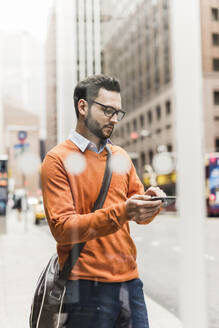 Geschäftsmann benutzt Smartphone auf der Straße - UUF30947