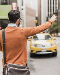 Businessman standing on street and hailing taxi - UUF30948