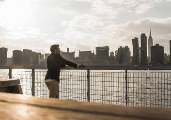 Geschäftsmann lehnt sich an ein Geländer in der Nähe des Hudson River in New York City, USA - UUF30954