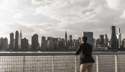 Junger Geschäftsmann mit Blick auf die Skyline von New York City in den USA - UUF30955