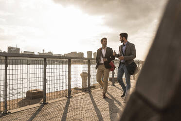 Young business colleagues talking by Hudson river in New York City - UUF30958