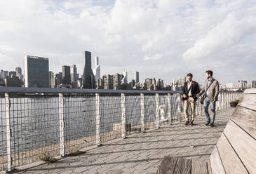 Junge Geschäftsleute spazieren am Hudson River bei Sonnenuntergang in New York City - UUF30959