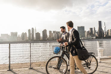 Young businessmen walking by Hudson river in New York City, USA - UUF30970