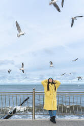 Carefree woman having fun near sea with seagulls flying in mid-air - OLRF00086