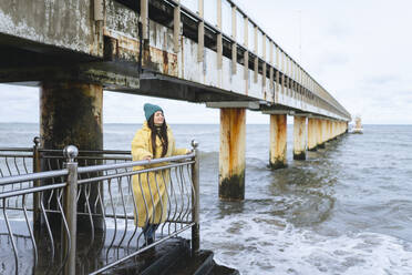 Carefree woman standing near railing at sea - OLRF00099