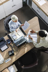 Multirassische Geschäftskollegen, die am Schreibtisch im Büro sitzen und eine Strategie planen - IKF01535