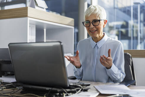 Businesswoman doing video conference through video call at desk in office - IKF01573